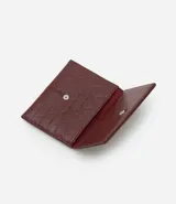 Billetera sobre color bordó con textura de triángulos en relieve y separadores internos para tarjetas y documentos.