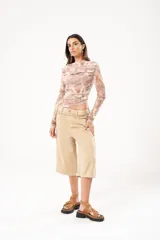 Bermuda de jean color beige, tiro medio, con bolsillos delanteros y traseros.