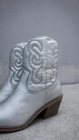 Bota corta plateada de estilo texano con bordados en el caño, taco de madera y cierre lateral.