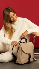 Mochila color beige de nylon con tapa y broche. Incluye bolsillos interiores, bolsillos laterales de fácil acceso, correas regulables y bolsillo en la espalda.
