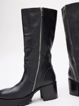 Bucanera de cuero vacuno color negro, con punta cuadrada, taco de madera de 7cm y detalle de hebillas al final de la caña.