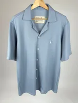 Camisa celeste tejida de algodón con cuello clásico, manga corta y cierre frontal con botones.