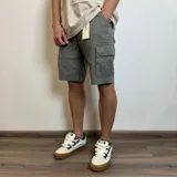 Bermuda cargo color gris verdoso, de gabardina, con bolsillos laterales con solapa y bolsillos traseros.