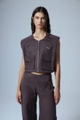 Pantalón cargo marrón de gabardina, con cierre metálico lateral, elástico en cintura trasera, recortes delanteros y bolsillos tipo cargo.