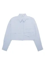 Camisa cropped de popelina a rayas celestes y blancas, de manga larga y corte holgado. Presenta cuello clásico, cierre frontal con botones y bolsillos de parche en el pecho.