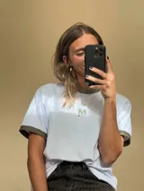 Remera blanca de algodón con cuello redondo y mangas cortas con puños de lurex dorado.