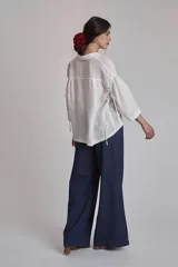 Camisa blanca de lino con cuello clásico, cierre frontal con botones y mangas 3/4 abullonadas.