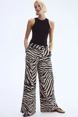 Pantalón amplio de sarga con estampado de cebra en tonos beige y negro, tiro alto, bolsillos al bies y cierre con botón y corchete ocultos.