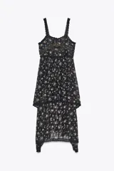 Vestido negro con estampado floral, escote recto y tirantes finos. Detalle de aplicación de hilo metalizado, lentejuelas y puntilla combinadas a tono. Bajo asimétrico.