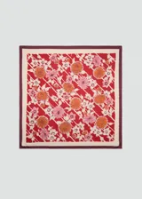 Pañuelo cuadrado con estampado de flores en tonos naranja, rosa y blanco sobre fondo rojo. Tiene un borde liso en color crema y un borde exterior en color borgoña.