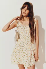 Vestido corto blanco con estampado de naranjas, breteles anchos y escote en U. Presenta frunces en el busto y falda con volados.