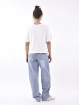 Remera blanca de manga corta con cuello redondo y estampado frontal que dice "SAVAGE" con una figura de animal (posiblemente un leopardo o jaguar) hecho de lentejuelas o material brillante. Debajo del estampado principal se lee "LIFE GOES ON ENJOY".