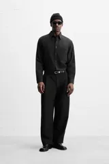 Camisa color crema de corte relaxed fit, confeccionada en tejido de mezcla de algodón suave al tacto. Tiene cuello solapa, manga larga con puños abotonados, un bolsillo de parche en el pecho y cierre frontal con botones.
