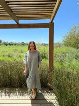 Vestido largo color beige, de corte amplio, con mangas cortas abullonadas y volado en el ruedo.