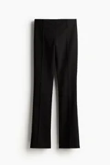 Pantalón de sarga negro con cierre oculto y corchete en un lateral, y bolsillo ribeteado decorativo atrás. Piernas ajustadas de corte recto con abertura en la parte posterior del bajo y pliegues cosidos adelante y atrás.