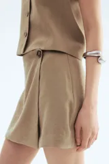 Short pollera color beige, de corte mini y diseño cruzado con botón decorativo.