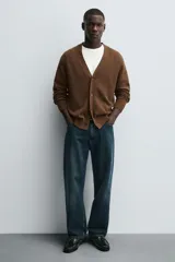 Mocasín de vestir de cuero color verde oscuro, con borlas decorativas en el empeine, punta redondeada y suela con ligero tacón.