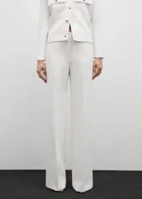 Pantalón blanco de corte recto y largo, con forro interior, tejido fluido, dos bolsillos laterales y cierre oculto de botón, gancho y cremallera.