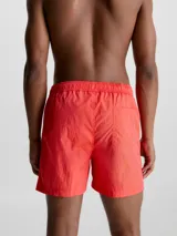 Short de baño rojo coral de largo medio, con cintura elástica y cordón ajustable. Incluye bolsillos laterales y trasero, forro de malla y logo de Calvin Klein en el lateral.