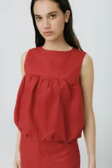 Top musculosa de lino color rojo, con cuello redondo y diseño estilo balloon con volumen en el ruedo. Cuenta con cierre de botones en la parte trasera.
