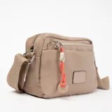 Bandolera color beige con correa larga regulable, cierre superior y bolsillo frontal con cierre.