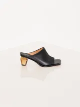 Sandalia de cuero vacuno color negro, con taco de acrílico diseñado para la colección y costuras en punto cruz, forrada en cuero.