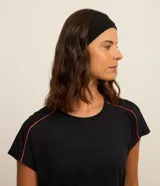 Top deportivo negro de poliamida, con escote redondo y breteles medianos. Presenta detalle contrastante color naranja en el bajo y en los bordes de las mangas.