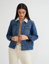 Campera de jean azul con cuello y forro de corderito color crudo, corte clásico y botones metálicos.