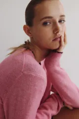 Saco corto de punto fino, color rosado, con escote redondo, cierre frontal con botones y detalles de ribetes en contraste en cuello, puños y ruedo.