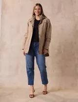 Campera impermeable color gris claro, marca Gallery. Tiene abertura central con cierre oculto y botones a presión, bolsillos delanteros y capucha plegable en el cuello.