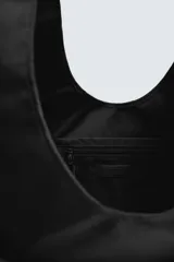Bolso shopper negro de hombro fabricado en tejido técnico. Tiene un compartimento principal sin cierre, un bolsillo plano y otro con cierre mediante cremallera en el interior. En la parte frontal tiene dos bolsillos con cierre mediante imán y asa de mano.