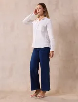 Camisa blanca de manga larga con cuello con solapa y abertura central con botones. Tiene dos bolsillos delanteros aplicados.
