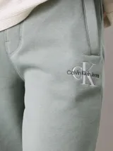 Pantalón de chándal de felpa color verde agua, con cintura elástica ajustable con cordón, puños de canalé, bolsillos laterales y trasero, y logo bordado de Calvin Klein en la pierna.