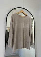Sweater color visón con cuello redondo, bolsillos delanteros y punto elástico en puños y bajo.