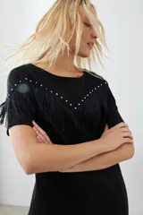 Vestido corto negro con flecos en el pecho y tachas plateadas en los hombros.