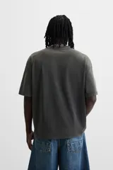 Camiseta negra con efecto lavado, cuello redondo, manga corta y estampado de estrella con texto en el centro.
