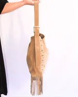 Bandolera de cuero color beige con flecos y tachas plateadas.