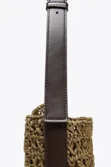 Bolso tipo saca de rafia color marrón con asa de hombro ajustable y detalle lateral. Incluye cartera con bolsillo extraíble y cierre con botón imantado.