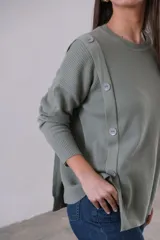 Sweater verde oliva de punto, corte recto y cuello redondo. Presenta detalle de botones en el hombro.