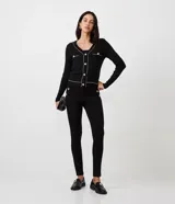 Pantalón legging negro de punto roma, con cintura alta y botones metalizados decorativos en los laterales.