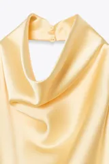 Top color amarillo claro de satén con cuello halter y espalda descubierta. Cierre trasero con botones ocultos.