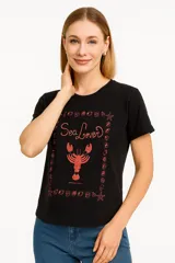 Remera celeste de manga corta y cuello redondo, con estampado de sardinas sobre fondo a cuadros rojos y blancos. Incluye texto con los nombres de las ciudades de Cagliari y Sardina.