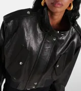 Campera bomber corta de cuero sintético negro, con cuello alto, cierre frontal, hombreras con botones a presión y bolsillos con solapa y botón a presión.