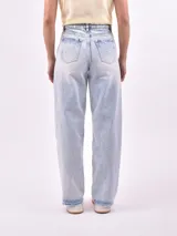 Jean de mezclilla celeste con lavado ácido y efecto desgastado. Modelo de tiro alto y corte ancho (wide leg) con ruedo deshilachado.