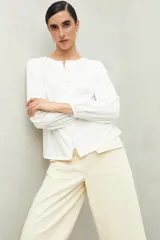 Camisa celeste de corte holgado con botones frontales, canesú con tablas y mangas 3/4 amplias con puño elastizado.