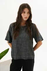 Blusa color crudo de lino con cuello redondo y mangas cortas.
