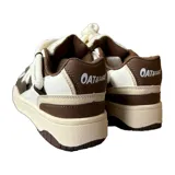 Zapatillas bajas de cuero ecológico color blanco y marrón con cordones gruesos blancos.