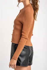 Cardigan negro de tejido de punto acanalado, con cuello polo, corte al cuerpo y cierre frontal con botones.