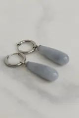 Par de aros colgantes con argolla de acero quirúrgico hipoalergénico y dije en forma de gota de piedra natural color marrón.