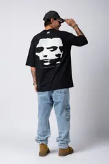 Remera negra de corte amplio con mangas cortas y estampado pequeño con texto en el frente.